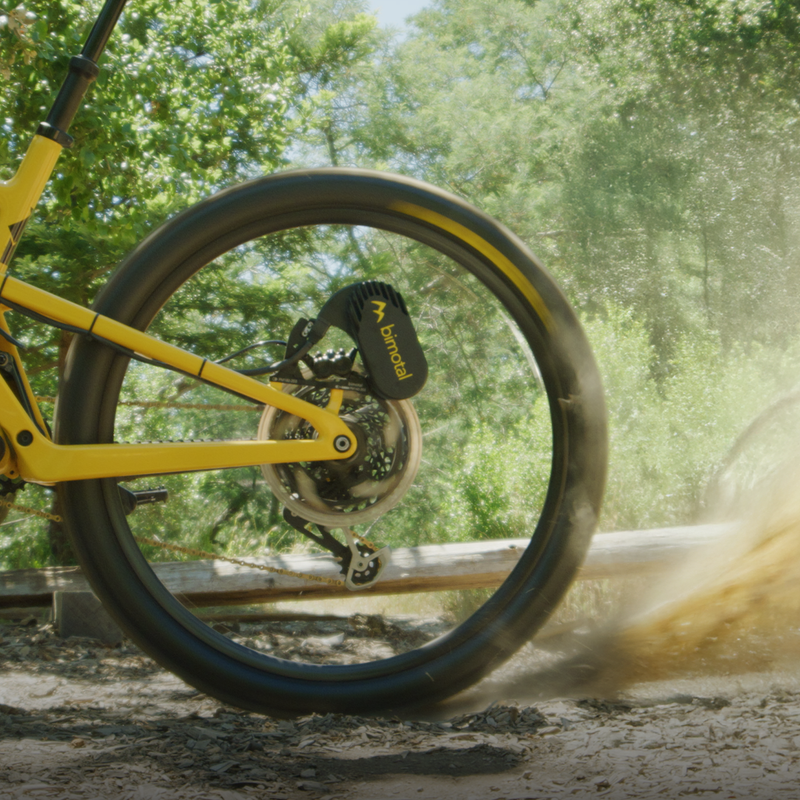 Yellow bicycle wheel in motion with a blurred background of greenery